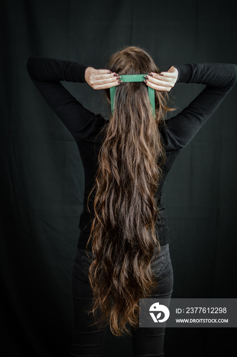 Proud of my long natural hair - Young woman from behind holding a small framein her long hair