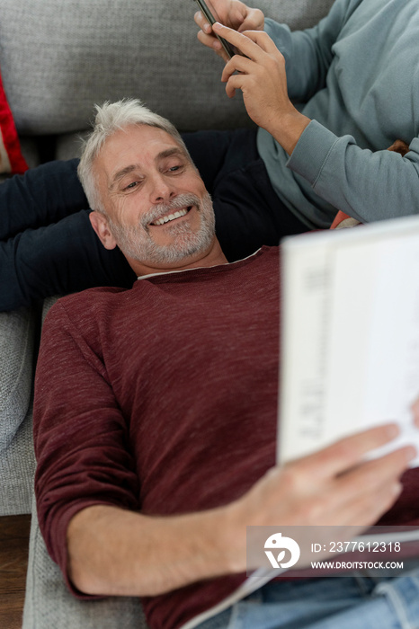 Smiling male couple relaxing on sofa at home