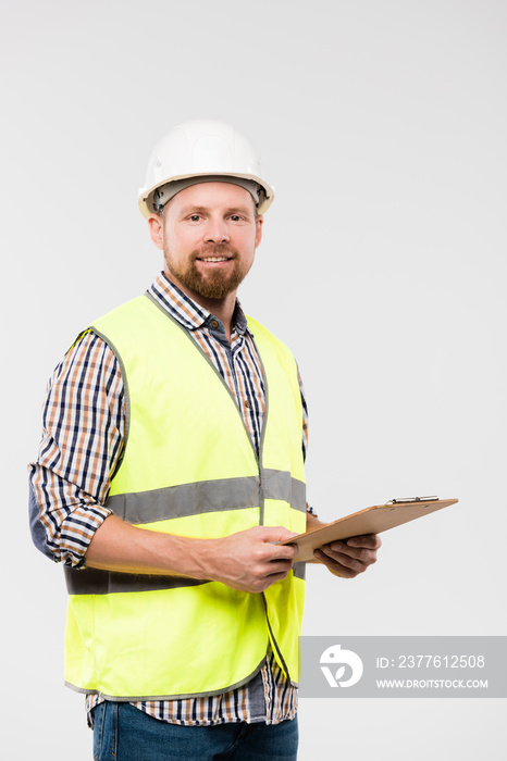 Cheerful young foreman or engineer with clipboard standing in isolation