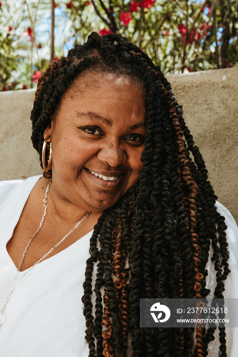 portrait of a plus size afro latinx haitian american woman smiling with textured hair and gold earring