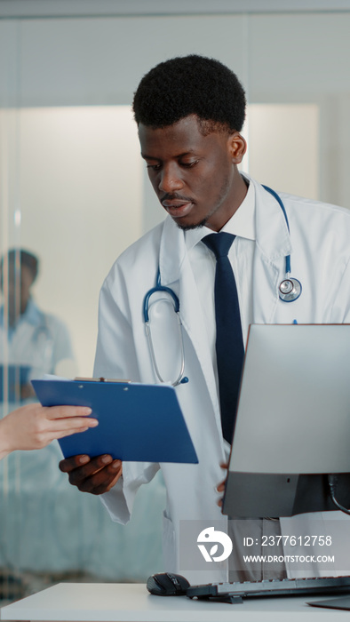 Man working as doctor using computer and documents to cure patient with disease in hospital ward. Physician looking at monitor while nurse helping with papers. Healthcare specialist