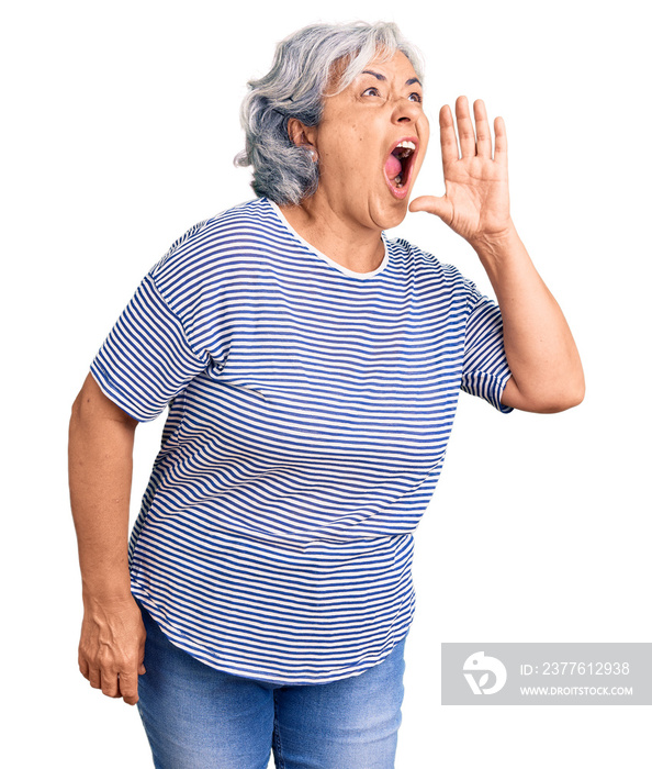 Senior woman with gray hair wearing casual striped clothes shouting and screaming loud to side with hand on mouth. communication concept.