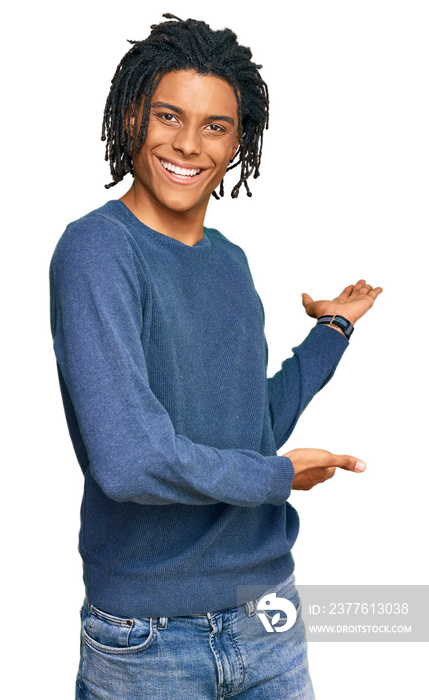 Young african american man wearing casual winter sweater inviting to enter smiling natural with open hand