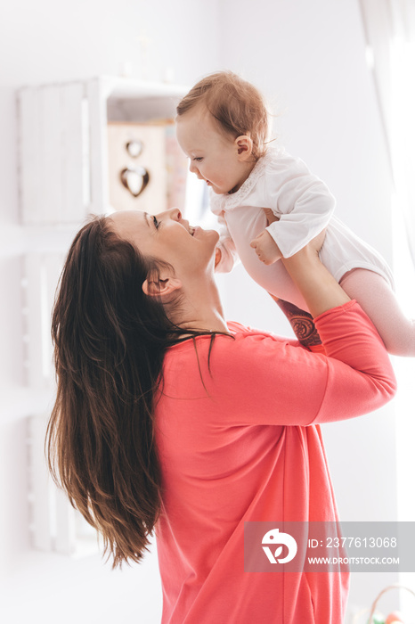 Young woman lifting her baby daughter up.