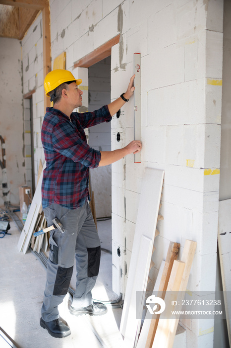 drywall worker with yellow safety helmet works on building site in a house