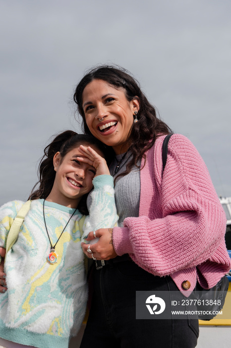 Portrait of smiling mother and daughter looking away on sunny day