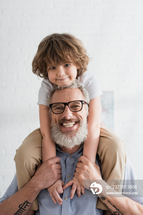 Cheerful boy and grandfather smiling at camera