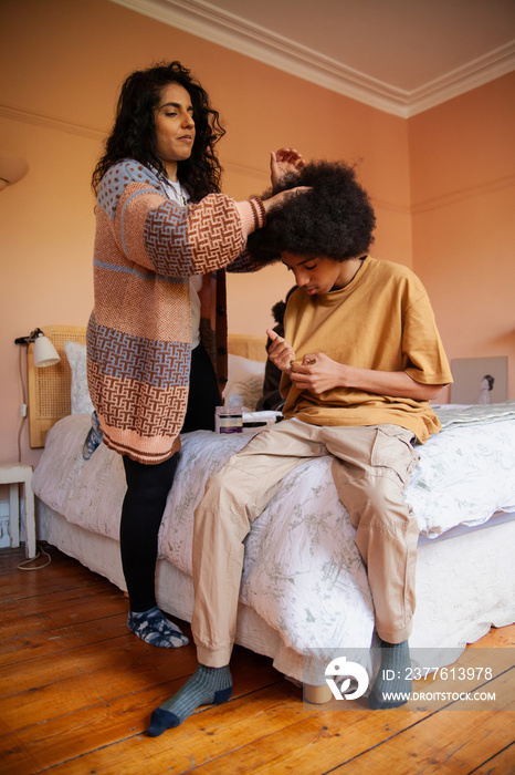 Mid-sized mother helping her son with his hair in the bedroom