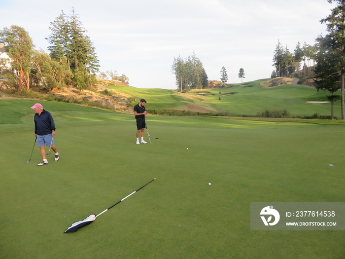 A father and son on a putting green playing golf surrounded by beautiful scenery outside of Victoria, British Columbia, Canada.