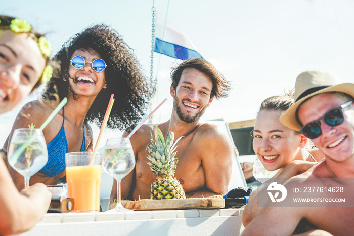 Group of happy friends drinking tropical cocktails at boat party - Young people having fun in caribbean sea tour eating pineapple and laughing - Youth and summer vacation concept