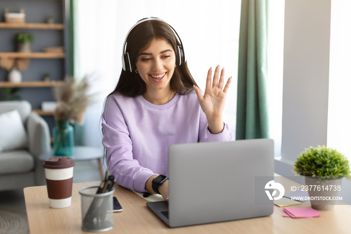 Cheerful woman having video call using laptop and talking