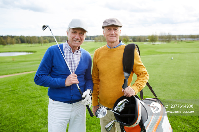 Small group of active senior buddies in casualwear standing in green field for outdoor recreation