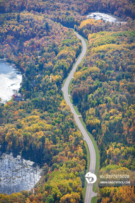 Aerial view of curving road and lakes and trees in northern Minnesota on a sunny autumn day