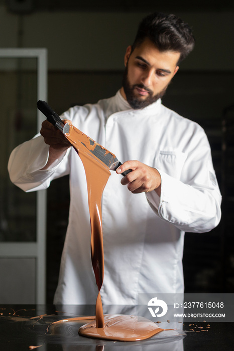 Pastry chef working on tempering chocolate on marble table