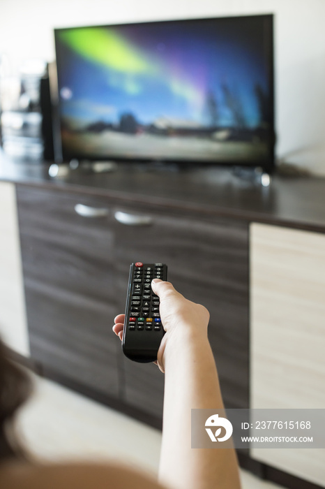 Hand hold TV remote control. Watching television.