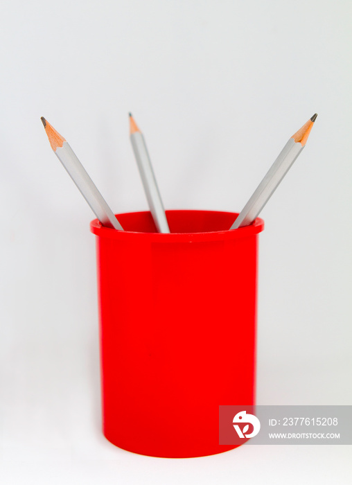 Red plastic pencil holder with pencils. School and student material.