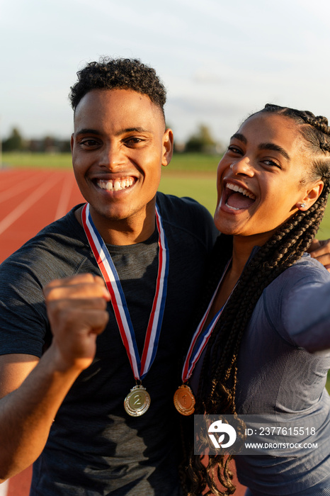 Portrait of male and female athlete celebrating with medals