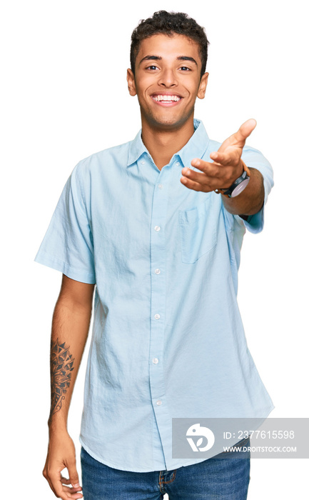 Young handsome african american man wearing casual clothes smiling friendly offering handshake as greeting and welcoming. successful business.