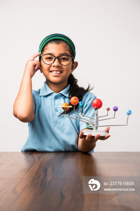 Indian Schoolgirl / girl child studying Planets or planetary science with 3d Model of our solar system