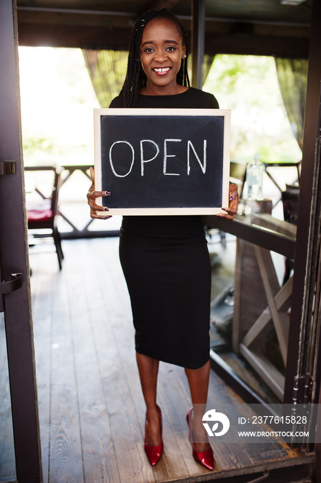 African american woman hold open welcome sign board in modern cafe coffee shop ready to service, restaurant, retail store, small business owner.