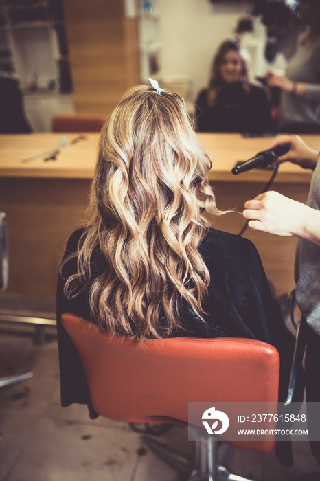 Beautiful hairstyle of young woman after dying hair and making highlights in hair salon.