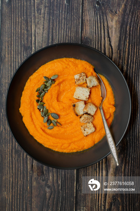 Creamy pumpkin soup in a plate. Wodeen background