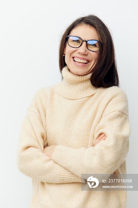 portrait of a beautiful cute woman in a beige sweater on a light background in glasses for vision with arms crossed on her chest