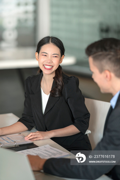 Two young business people talking together with happiness at work.