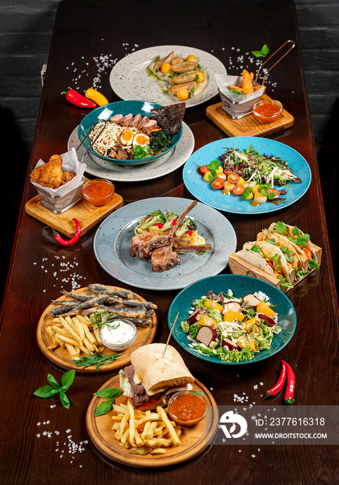 Different colorful meals on dark wooden table in the restaurant.