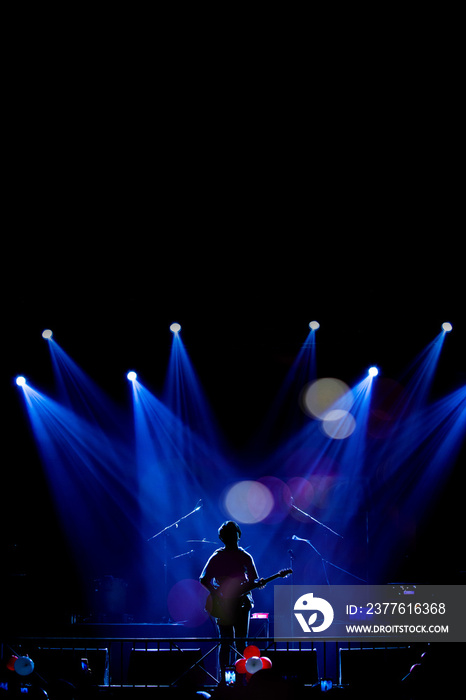 Asian Musician playing the guitar on black background with spot light and lens flare, musical concept