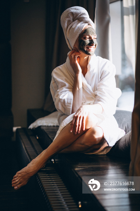 Woman with black mask on face in bathrobe