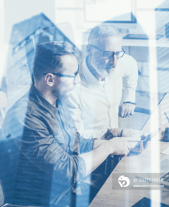 Double exposure concept.Team of business people making great work discussion in studio.Young bearded man showing mobile phone to adult businessman.Skyscraper office building on blurred background.