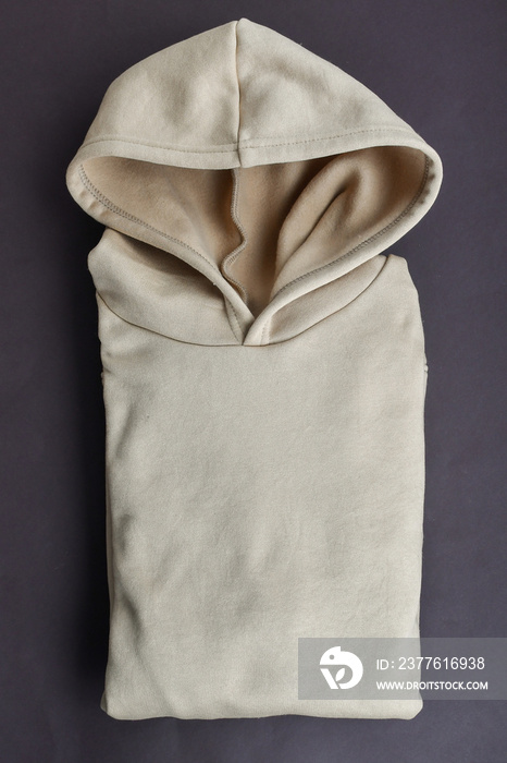 Top view of light beige hoodie on dark background.