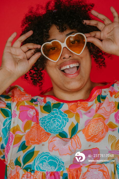 closeup of a plus size black person holding heart sunglasses