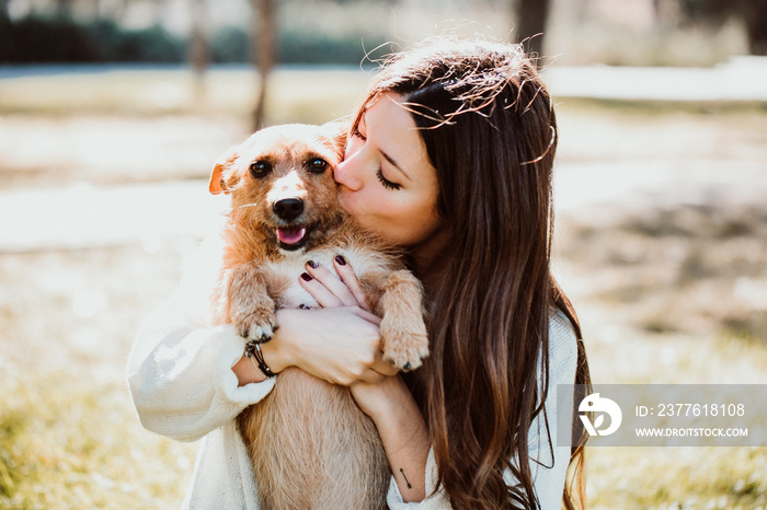 .Beautiful young woman playing outdoors with her little brown adopted dog. Hugs and kisses. Dogfriendly concept. Lifestyle.