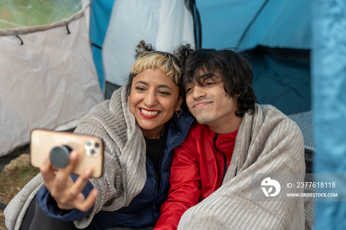 Mother and son taking selfie in tent