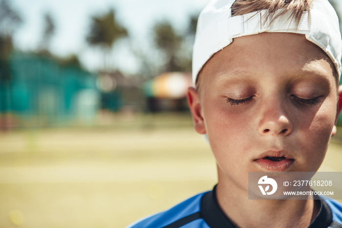 Portrait of calm young boy with closing eyes expressing tranquility while walking outside. Copy space