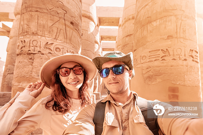 A couple in love takes a selfie photo among the giant columns in the Karnak Temple in Luxor during the honeymoon tour