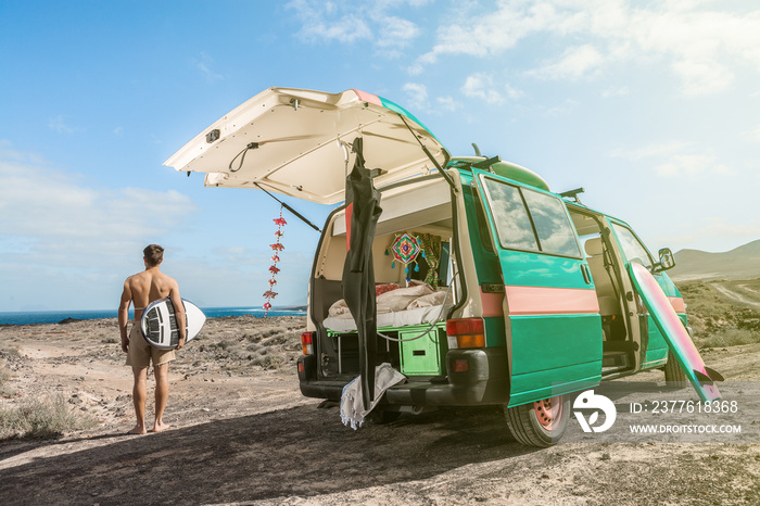 Surfer on seashore with camping van in sunlight