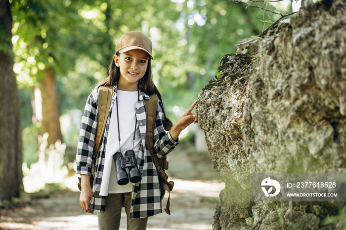 Young girl scout exploring parks with rucksuck and binoculars