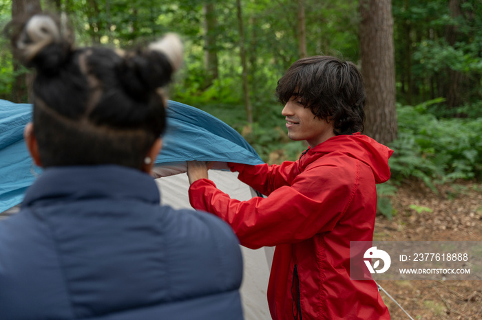 Mother and son setting up tent in forest