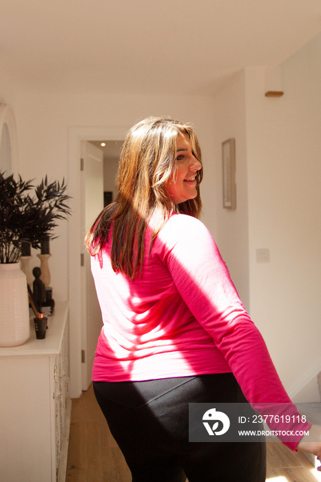 Confident plus-sized woman dancing in workout clothes at home