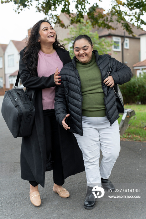 Mother walking with down syndrome daughter in residential district