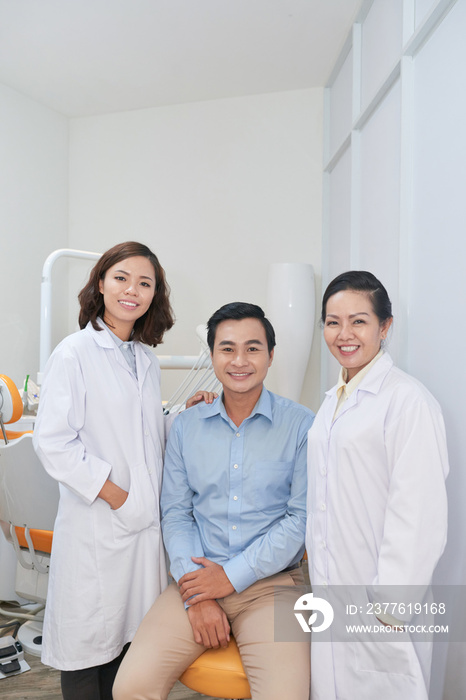 Happy young Asian man and his dentists smiling at camera