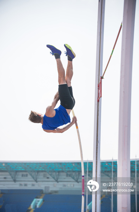 Pole vault - a young athletic man rest against the ground on the pole and ready to jump