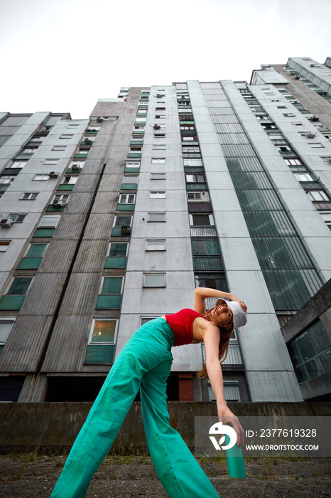 A teenage girl is posing on the street surrounded by buildings.