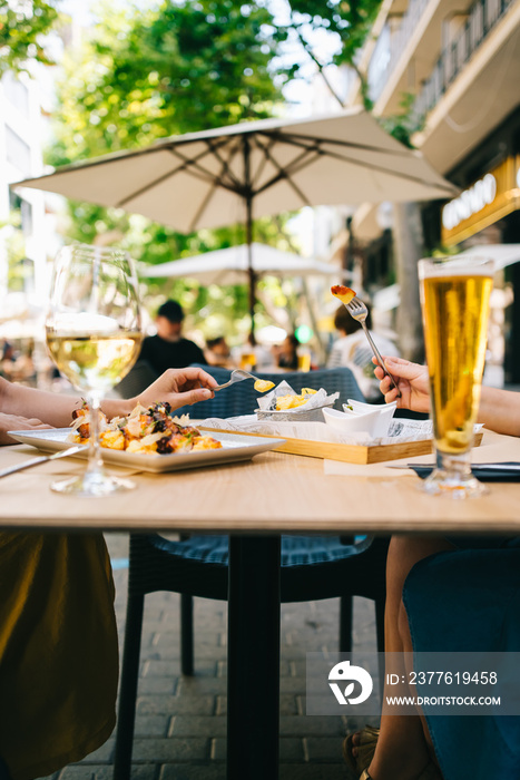 a glass of beer and wine on a table with dishes two girls have lunch together in a restaurant on the terrace