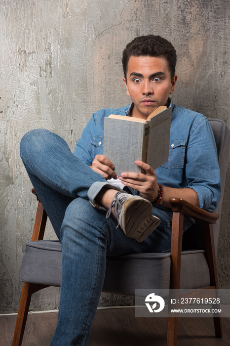 Young man reading a book and sitting on chair