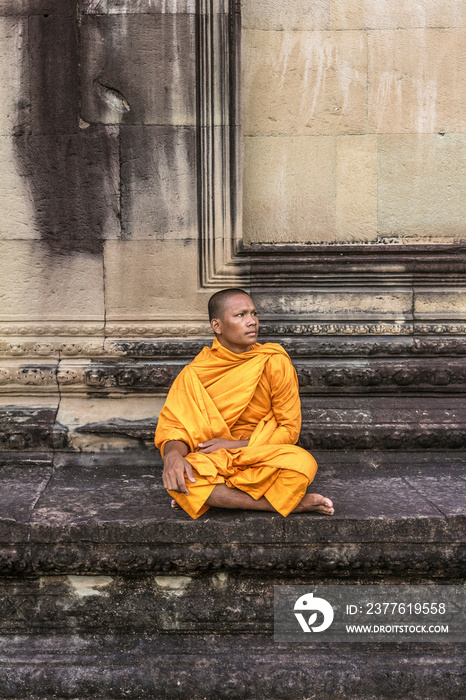 Young Buddhist monk sitting at temple in Angkor Wat, Siem Reap, Cambodia