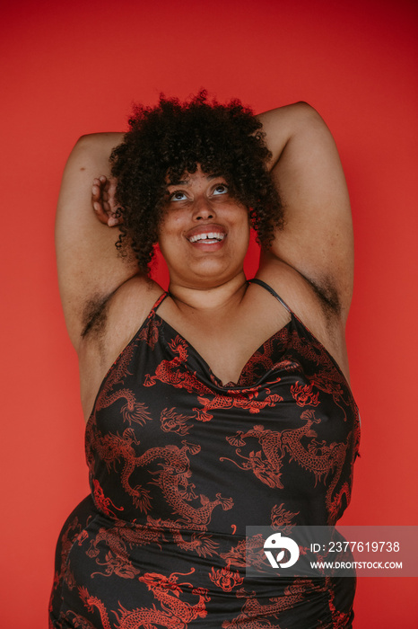 portrait of a plus size afro indigenous person arms crossed overhead smiling and looking up